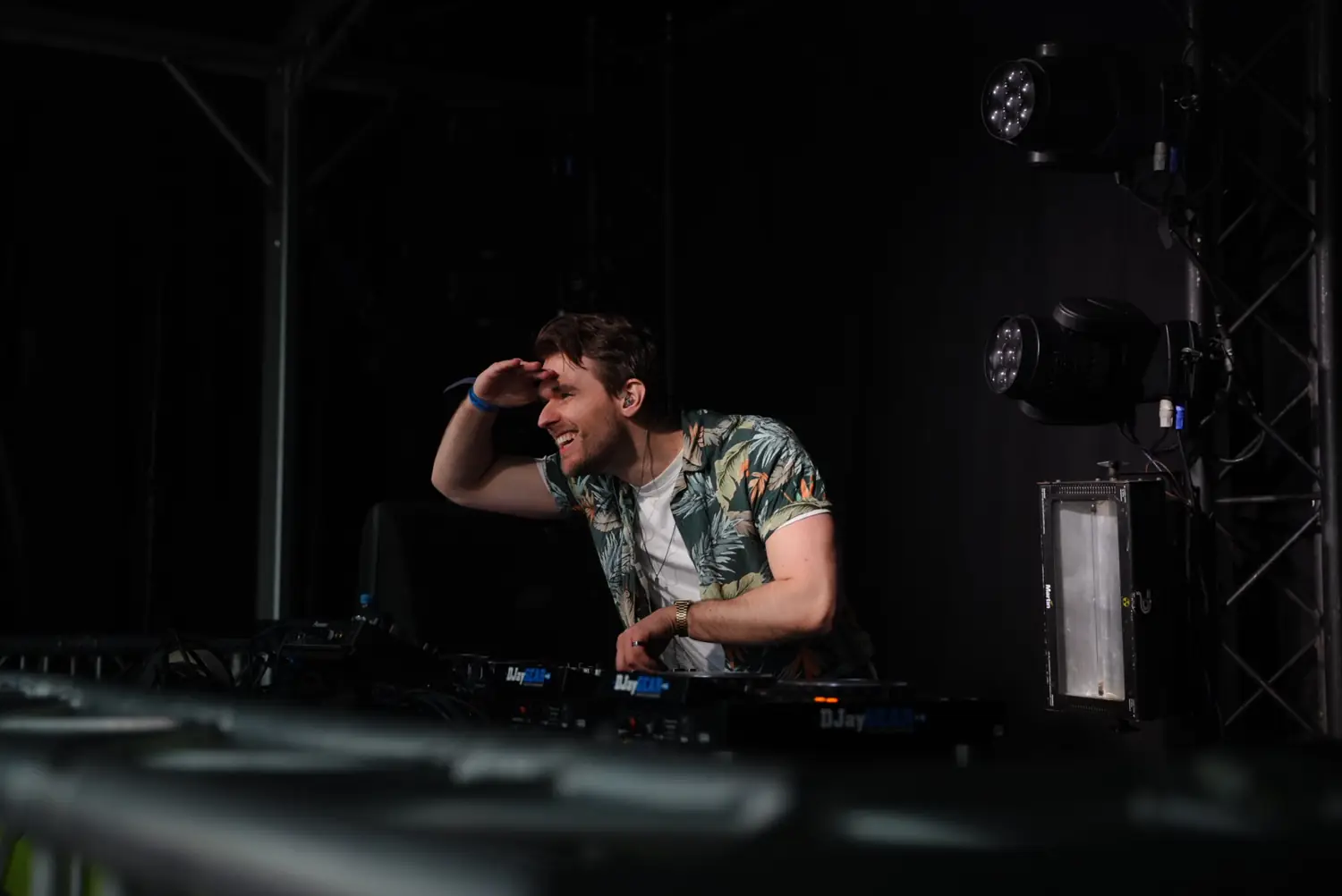 Laurentius performing a DJ set behind the decks under stage lighting